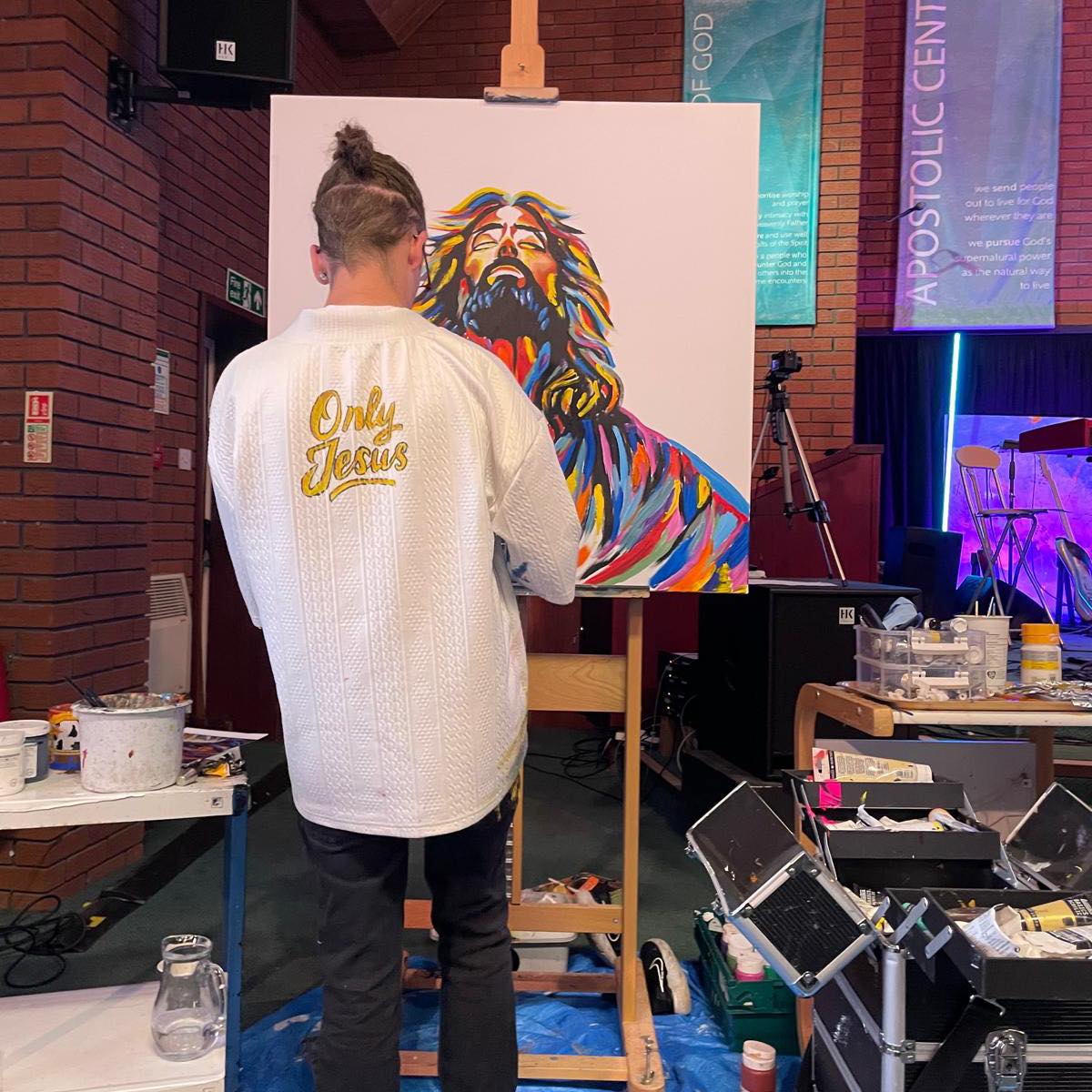 Dave painting jesus in many vibrant colours in a church building